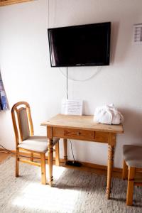 einem Holztisch mit einem Stuhl und einem TV an der Wand in der Unterkunft Gasthaus Freihof 
