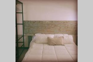 a bedroom with a white bed with a wooden headboard at Estudio Dos Orillas in Colonia del Sacramento