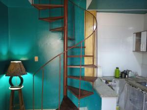 a wooden spiral staircase in a kitchen with a lamp at Casa de praia; Itapebussu, Guarapari, ES. in Guarapari