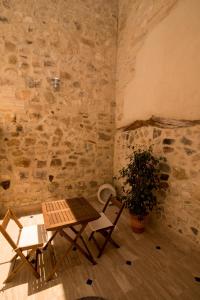 a table and chairs in a room with a stone wall at Posada de Momo in Benamejí