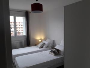 2 camas en una habitación blanca con ventana en La Grâce en Vaulx-en-Velin