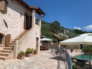 een huis met een zwembad en een patio met een parasol bij Domus Clara in Assisi