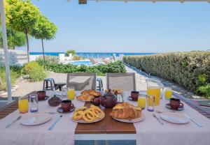 a table with plates of food and glasses of orange juice at Aegiali Sea View Villa in Gennadi
