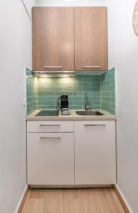 uma cozinha com armários brancos e um lavatório em Central Green Studio em Heraclião