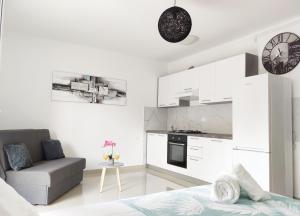 ein weißes Wohnzimmer mit einem Sofa und einer Küche in der Unterkunft White Studio Apartman in Pula