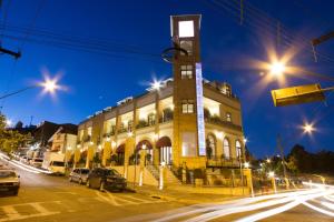 a building with a clock tower next to a street at Pousada Luis XV in Campos do Jordão