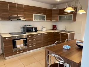 a kitchen with wooden cabinets and a wooden table with a dining room at Casa Andrei in 2 Mai