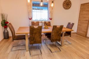 mesa de comedor con sillas y reloj en la pared en BergAufe Chalets Mallnitz, en Mallnitz