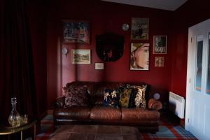 un sofá de cuero marrón en una sala de estar con paredes rojas en The Dairy Private Hotel by Naumi Hotels, en Queenstown