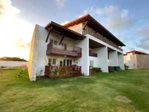 una casa con un prato verde davanti di Flat beira mar de Carneiros 2 quartos a Praia dos Carneiros