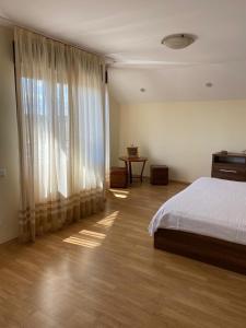 a bedroom with a bed and a large window at Casa Andrei in 2 Mai