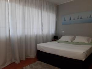 a bedroom with a large bed with white curtains at Apartamentos Matur in Machico
