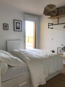 1 dormitorio con 1 cama con sábanas blancas y ventana en Appartement neuf Grande terrasse en Capbreton