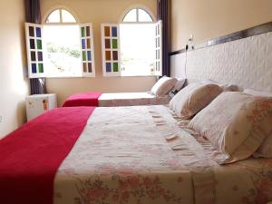 a bedroom with a large bed and two windows at Pousada da Villa in Lençóis