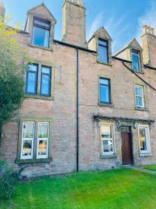 an old brick house with windows and a yard at Castle Grant Apartment in Inverness
