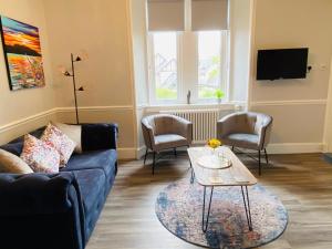 a living room with a blue couch and a table at Castle Grant Apartment in Inverness