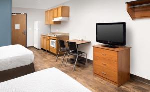 a hotel room with a television and a desk with a kitchen at WoodSpring Suites Allentown Bethlehem in Bethlehem