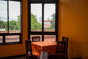 Vista Los Volcanes Hotel y Restaurante في Juayúa: طاولة مع كراسي في غرفة مع نوافذ