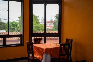 een tafel met stoelen in een kamer met ramen bij Vista Los Volcanes Hotel y Restaurante in Juayúa