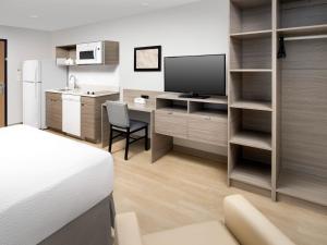 a bedroom with a bed and a desk with a television at WoodSpring Suites Seattle Tukwila in Tukwila