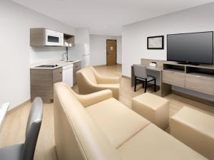a living room with a couch and a kitchen with a tv at WoodSpring Suites Seattle Tukwila in Tukwila