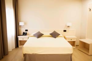 a bedroom with a white bed with two night stands at Hotel Palazzo Salerno in Roggiano Gravina