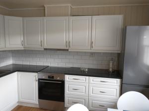 cocina con armarios blancos y lavavajillas negro en Leinastova, en Sandshamn