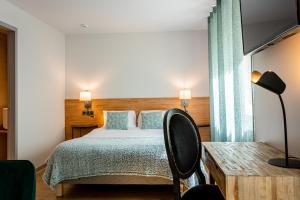 1 dormitorio con cama, mesa y TV en Hôtel L'Ouvrée, en Savigny-lès-Beaune