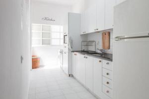 a kitchen with white cabinets and a white tile floor at Shantell Boutique Apartments in Netanya