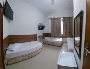 a bedroom with two beds and a tv in it at Suites Santa Terezinha in Aparecida