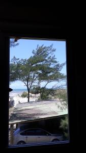 a window with a car parked in front of a tree at Beira mar Mariluz in Imbé