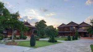 a house with a courtyard with trees in front of it at Baan Maneekan in Sukhothai