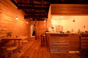 a kitchen with wooden walls and tables and a woman in the background at Hakone Guesthouse Toi in Hakone