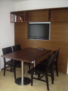 a dining room table with chairs and a flat screen tv at Appartements Christa in Dobbiaco