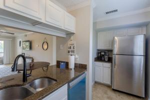 a kitchen with a stainless steel refrigerator and white cabinets at La Casa Del Mar 604 Star5Vacations in Dunedin