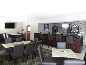 un restaurante con mesas y sillas y un bar en Cobblestone Inn & Suites - Harper, en Harper