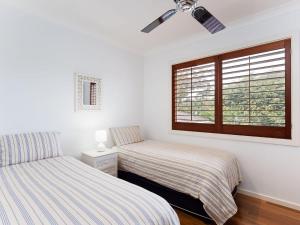 two beds in a room with a window at Beauty and the Beach', 88 Foreshore Drive - large home with WIFI & water views in Salamander Bay