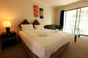 a bedroom with a large white bed with a window at Siesta Villa in Jindabyne