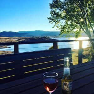 uma garrafa de vinho e um copo num banco em Siesta Villa em Jindabyne