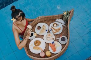 a woman sitting at a table with food in a pool at Sedok Jineng Villa Lembongan in Nusa Lembongan