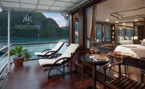 a balcony on a boat with chairs and a table at Orchid Classic Cruise in Ha Long