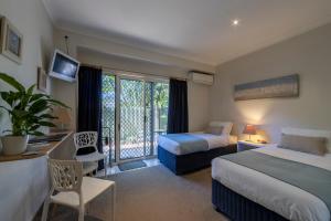 a hotel room with a bed, chair and a tv at Beachhouse Bed and Breakfast in Redcliffe
