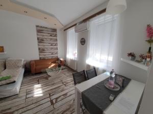 uma sala de estar com uma mesa e cadeiras e um sofá em Cozy apartment in the heart of Kecskemet em Kecskemét