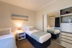 a hotel room with two beds and a mirror at Beachhouse Bed and Breakfast in Redcliffe