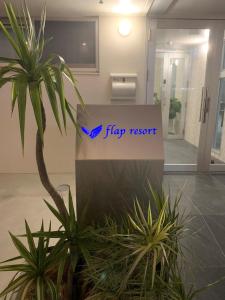 a sign for a flipp resort in an office with plants at Hotel Flap Resort in Chatan