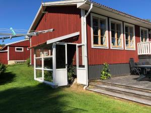 una casa roja con una puerta blanca y una terraza en Strandvägen 6B Stig en Järvsö