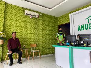 un homme assis au comptoir à côté d'un agent de sécurité dans l'établissement Anugrah Inn, à Nalagat