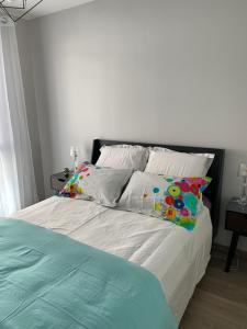 Una cama con sábanas blancas y almohadas en un dormitorio en Rodez Aveyron appart. T4 neuf 2 places parking en Rodez