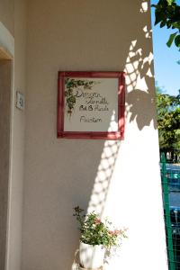 a sign hanging on a wall with a potted plant at Dimora Iannelli - B&B Rurale Paestum in Paestum