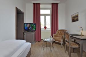 a living room filled with furniture and a tv at Hotel Stadt Hameln in Hameln